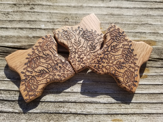 a photo of three wooden (oak) thread holder chips. Each thread holder has an overall square shape 
		with a rounded indent at the center of each edge to facilitate the wrapping of yarn or thread. Each thread holder has been laser engraved with 
		one-quarter of a lacy mandala design that features owls and vines, arranged so that the center of the mandala is at one corner. If you were to 
		arrange four thread winders in a two-by-two square you would have the entire mandala displayed.